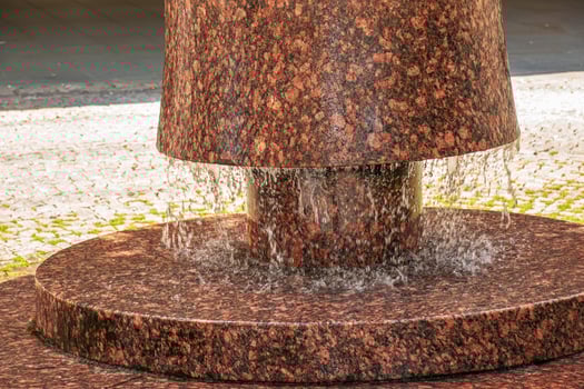 Granite fountain in the city of Nitra, in Slovakia. Drops of water on the background of flowing from the fountain. Details. photo