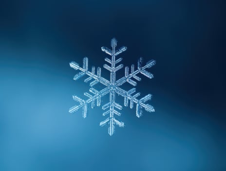Intricate snowflake against a deep blue background photo