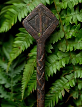 Carved wooden tribal totem against lush green foliage photo