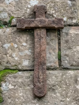 Weathered stone cross on old wall photo