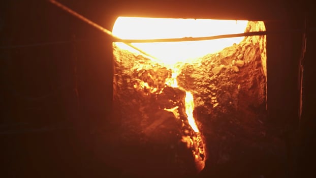 Molten metal is being poured out from a furnace in a detailed industrial process. Stock Clip photo