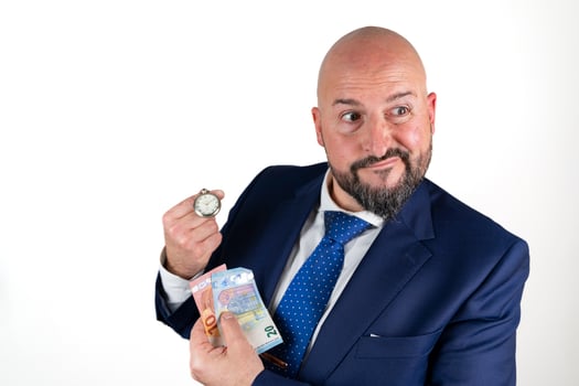 portrait of businessman in blue suit and tie with friendly expression showing a watch and banknotes isolated on white background photo