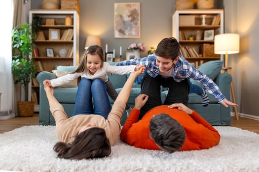 A family is playing on a rug in their living room photo