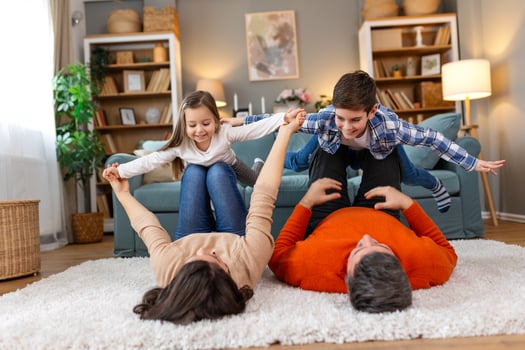 A family is playing on a rug in their living room photo