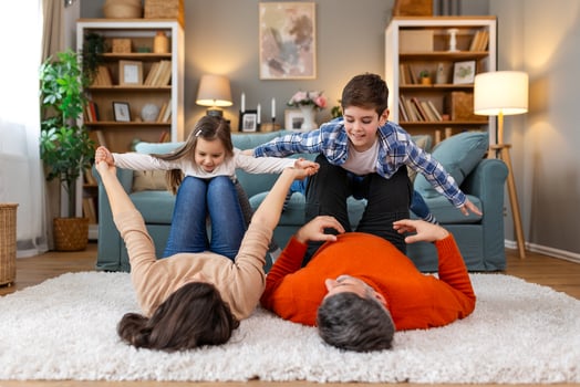 A family is playing on a rug in their living room photo