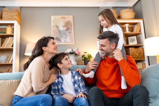 A family sitting on a couch in their living room photo