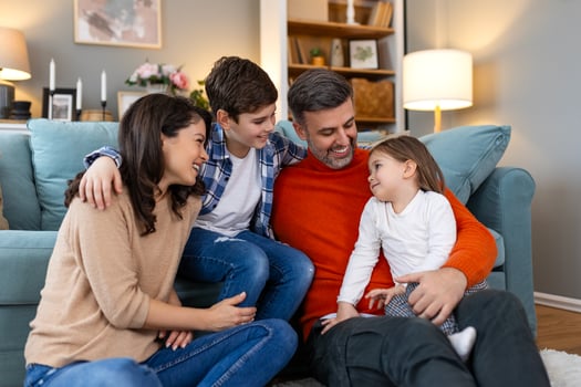 A family sitting on the floor in front of a couch photo