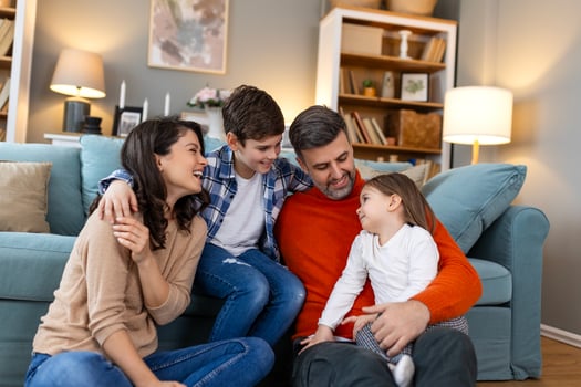A family sitting on the floor in front of a couch photo
