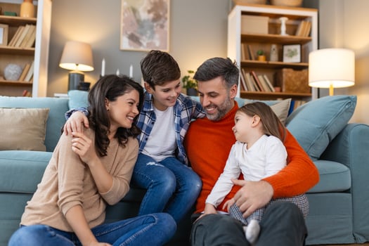 A family sitting on a couch in front of a book shelf photo