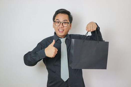 Cheerful young Asian man carrying many shopping bags on white background. photo