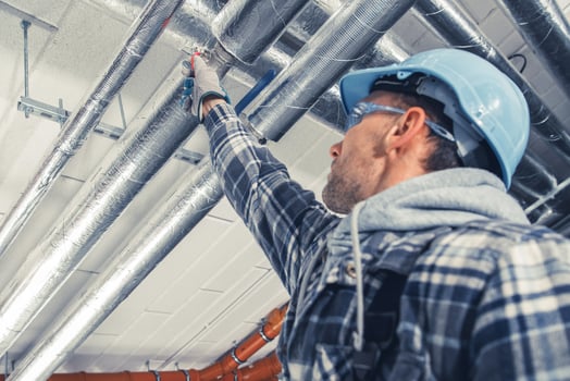 Man in Safety Gear Inspecting Overhead Pipes in a Construction Site During the Day photo