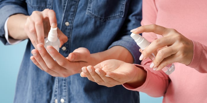 Virus Protection Concept. Unrecognizable Couple Applying Disinfectant Spray On Hands, Sanitizing Skin, Cropped Image, Closeup photo