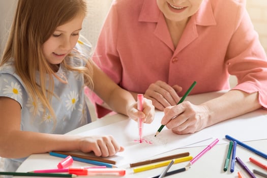 Family activities. Mature woman with her lovely granddaughter drawing Christmas tree together in kitchen photo
