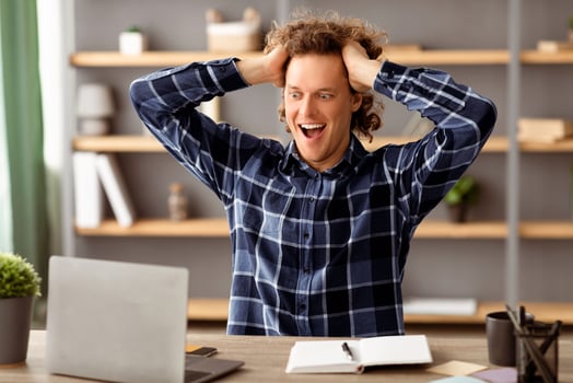 Business Success And Luck. Excited Businessman Looking At Laptop Touching Hair In Excitement Reading Great News Online Sitting At Workplace In Modern Office. Selective Focus photo