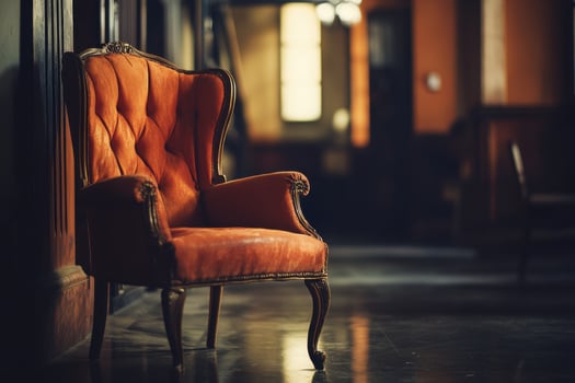 A vintage orange armchair stands alone in a dimly lit hallway. photo