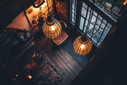 Two hanging globe lights illuminate a cozy living room with a wooden floor, rug, and a window. photo