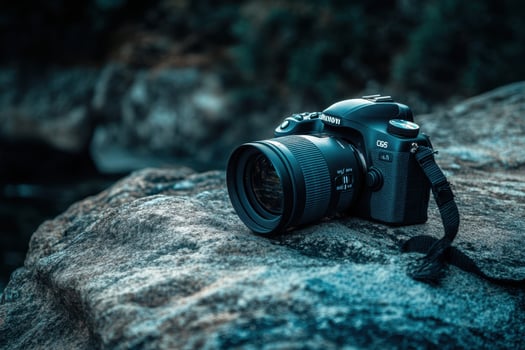 A DSLR camera on a rock by a river. photo