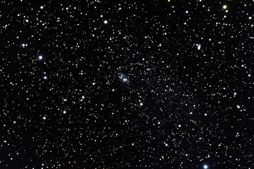 A faint, fuzzy galaxy visible amongst a field of stars. photo