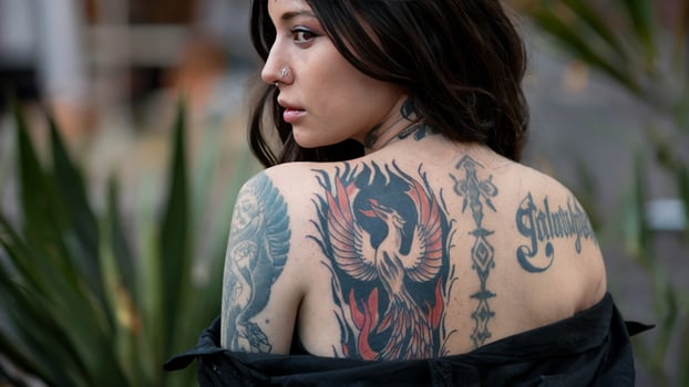 Woman displays phoenix tattoo on her back, symbolizing rebirth and strength through personal expression. Tattoo inspiration concept photo