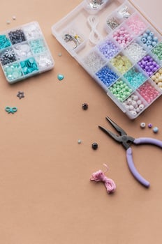 Crafting with colorful beads on a flat workspace with tools and containers in bright daylight photo