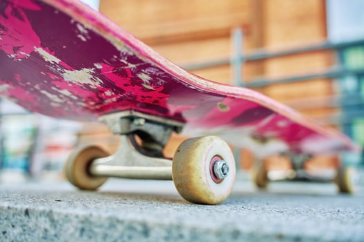 Used skateboard at city street, close up. Leisure activity and extreme sport concept photo