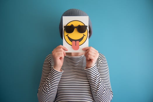 Card with smiley face hides persons face, playful tone against blue background photo