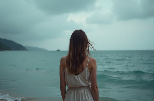 Woman stand ocean shore, look beautiful into distance at blue sea waves photo