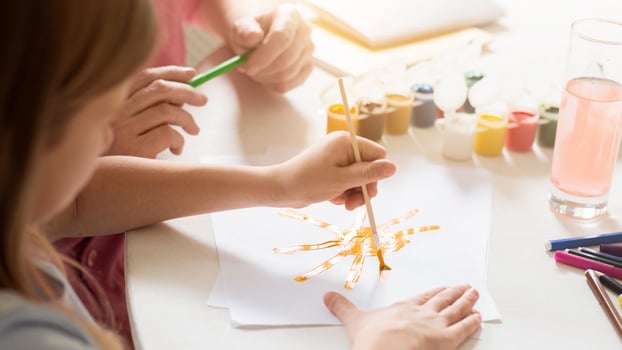 Family activities. Little girl and her grandmother painting together at table, closeup view photo