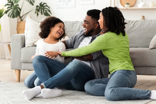 Cheerful black family having fun at home, parents tickling their daughter, laughing together, spending quarantine time in isolation, free space photo