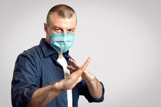 Coronavirus Protection. Man In Protective Medical Mask Standing In Ready To Fight Pose Over Gray Studio Background. Panorama, Selective Focus photo
