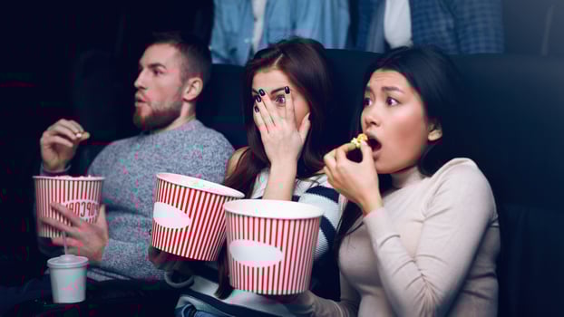 Leisure activity concept. Young people scared of horror movie in film theater photo