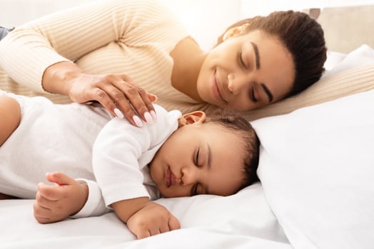 Loving Black Mom Hugging Sleeping Baby Lying In Bed In Bedroom At Home. Toddler Infant Sleeps Near Mom. Motherhood Lifestyle, Daytime Sleep Routine Concept. Selective Focus photo