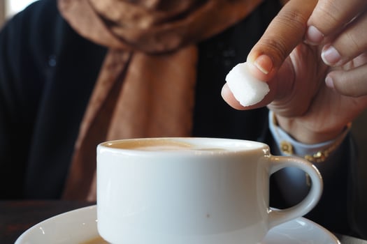 A Sugar Cube Delicately Being Added to a Warm Cup of Coffee, Enhancing the Experience photo