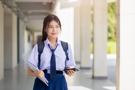 portrait school uniform teen girl standing happy smile indoor school campus. student day dream. photo