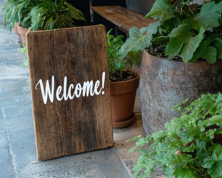 Welcoming sign and potted plants photo