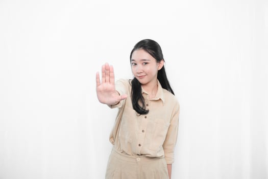 The expression of an Indonesian Asian model woman in white is smiling and making a stop sign photo