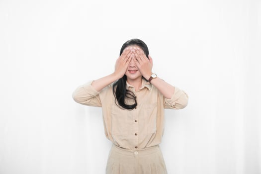 Expression of Indonesian Asian model woman in white dress covering both eyes with hands photo