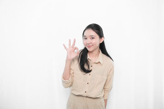 Expression of Indonesian Asian model woman in white dress smiling and making okay sign photo