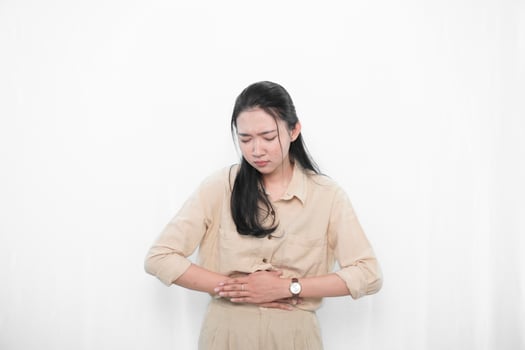 Expression of Indonesian Asian model woman in white dress having stomach ache photo
