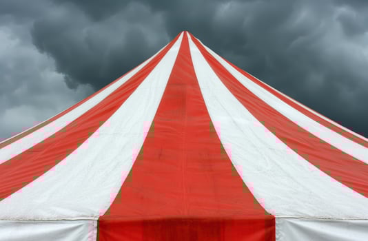 Dramatic storm clouds over a red and white circus tent photo