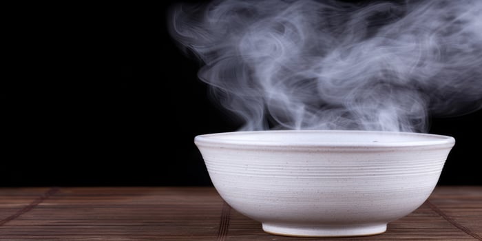 Steaming bowl of hot food on wooden table photo