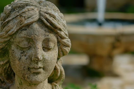 weathered stone face sculpture in garden photo