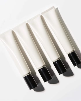 Four tubes of hand cream with black cap on a white surface photo