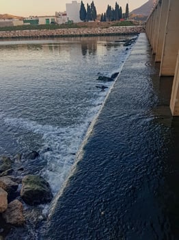 A wide waterfall current under a bridge in Wadi. Close to flowing water, discover complex details photo