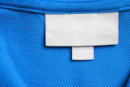 Blank white laundry care clothes label on blue shirt fabric texture background photo