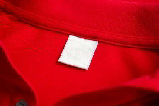 Blank white laundry care clothes label on red shirt fabric texture background photo