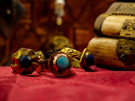 three reproductions of medieval rings decorated with precious gems on a red velvet background and a casket photo