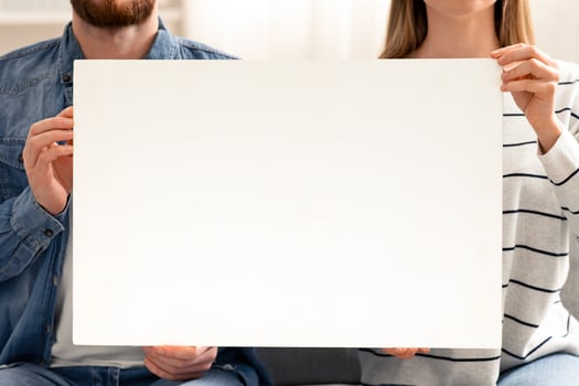 Quarantine information. Man and woman holding blank placard at home, empty space photo
