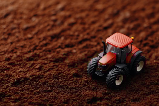 A miniature red tractor on rich brown soil, symbolizing agricultural endeavors. photo