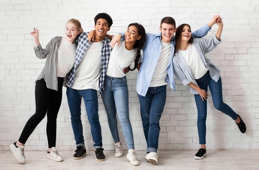 Friends embracing and having fun over white brick wall, posing to camera photo